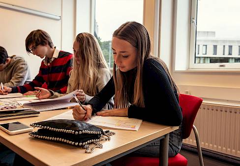 ISSFT student writing at her desk in the classroom