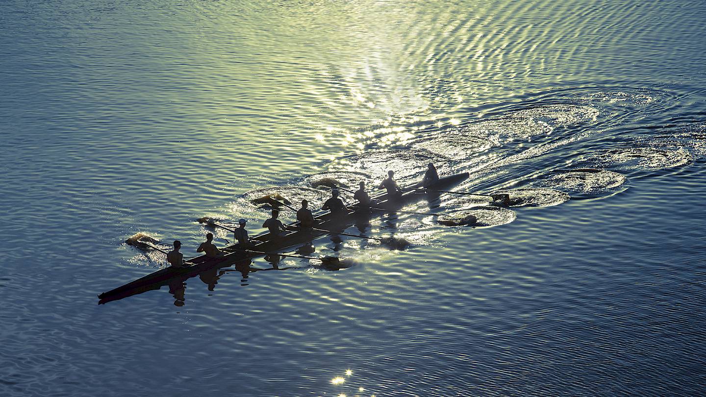 8 rowers in one rowing boat gliding down a river